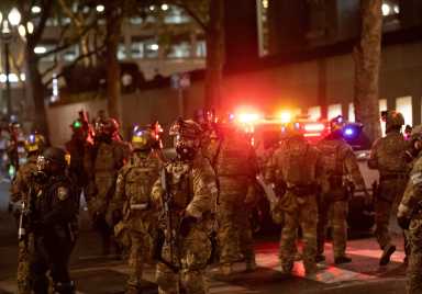Federal law enforcement officers deployed under the Trump administration’s executive order face off with protesters