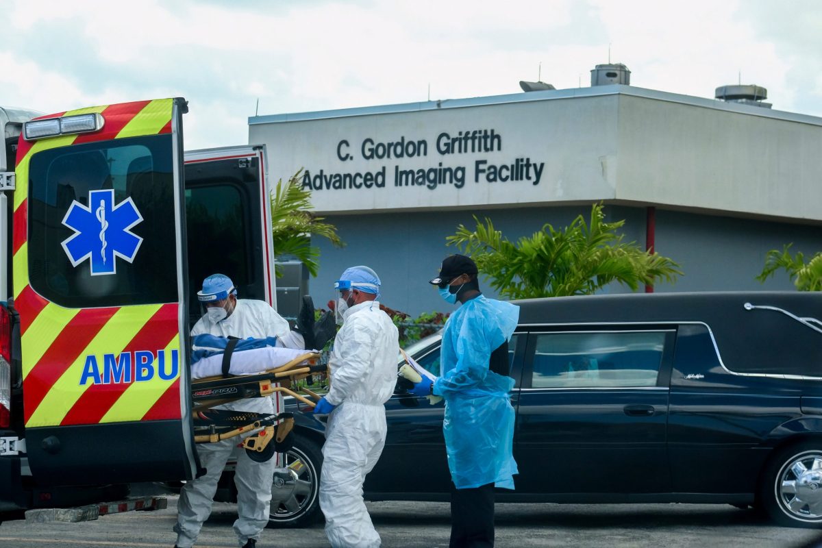 FILE PHOTO: Emergency Medical Technicians (EMT) arrive with a patient while a funeral car begins to depart at North Shore Medical Center where the coronavirus disease (COVID-19) patients are treated, in Miami