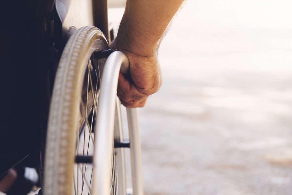 Closeup photo of Young disabled man holding wheelchair outside in nature