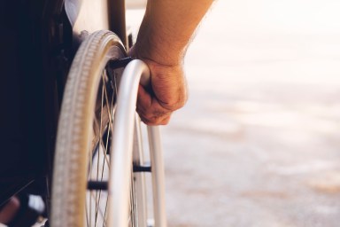 Closeup photo of Young disabled man holding wheelchair outside in nature