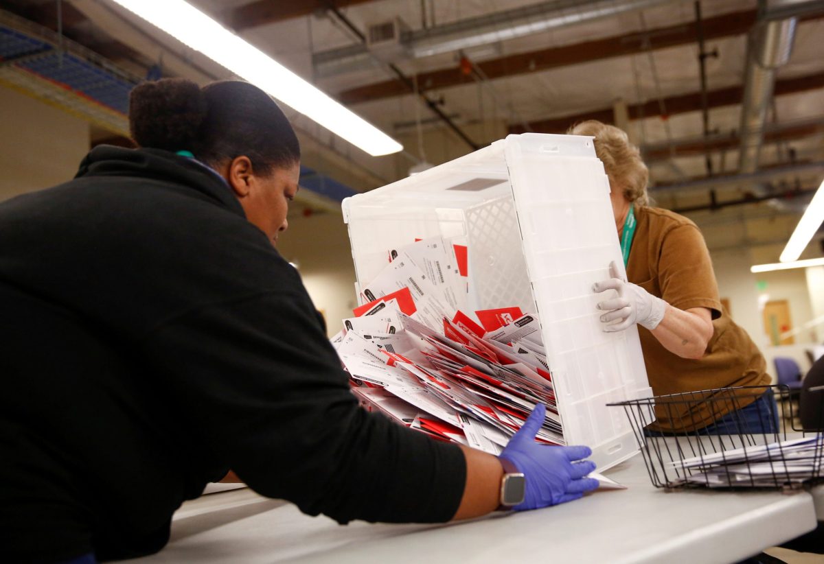 FILE PHOTO: Workers empty a carton of ballots from a drop box to prepare them for the mail sorting machine during the presidential primary at King County Elections ballot processing center in Renton