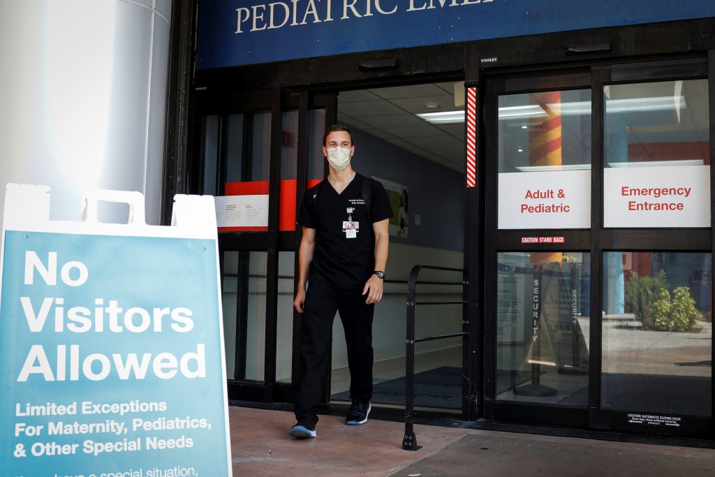 Dennis D’Urso, a resident ER doctor at Jackson Memorial Hospital, walks through a door during his shift amid an outbreak of the coronavirus disease (COVID-19), in Miami