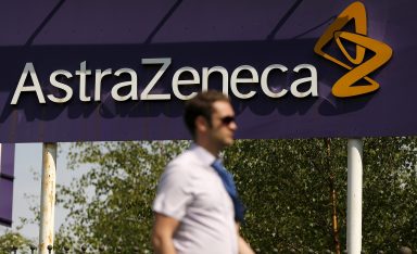 FILE PHOTO: A man walks past a sign at an AstraZeneca site in Macclesfield