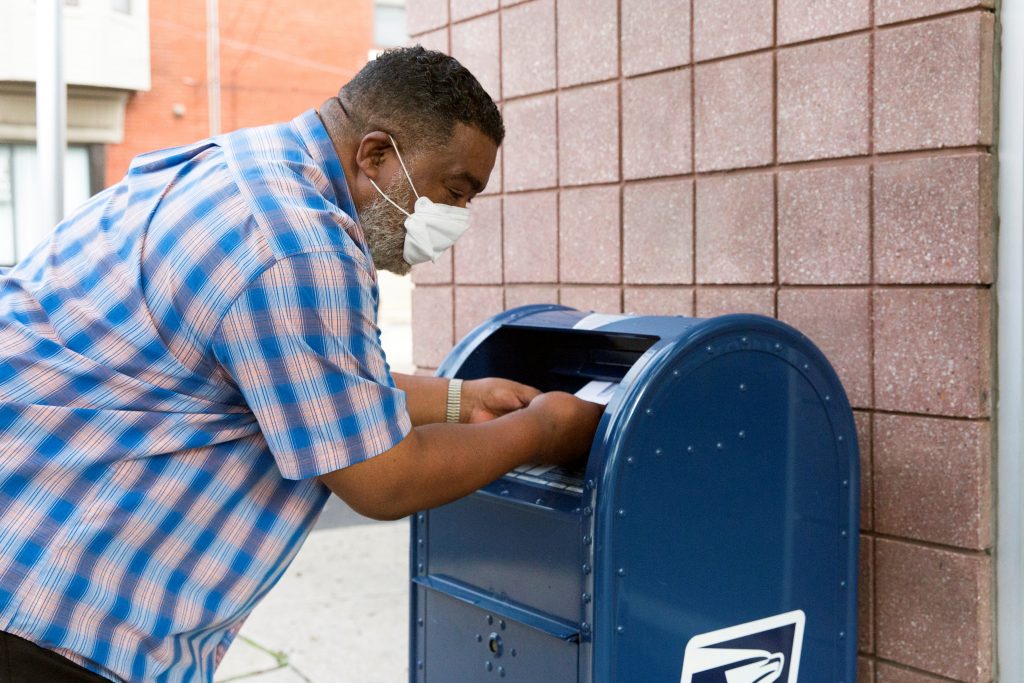 An individual deposits letters into a U.S. Postal Service (USPS) collection mailbox in Philadelphia