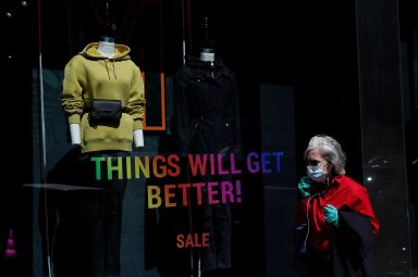 A woman walks by a clothing sales sign along Madison Avenue in New York City