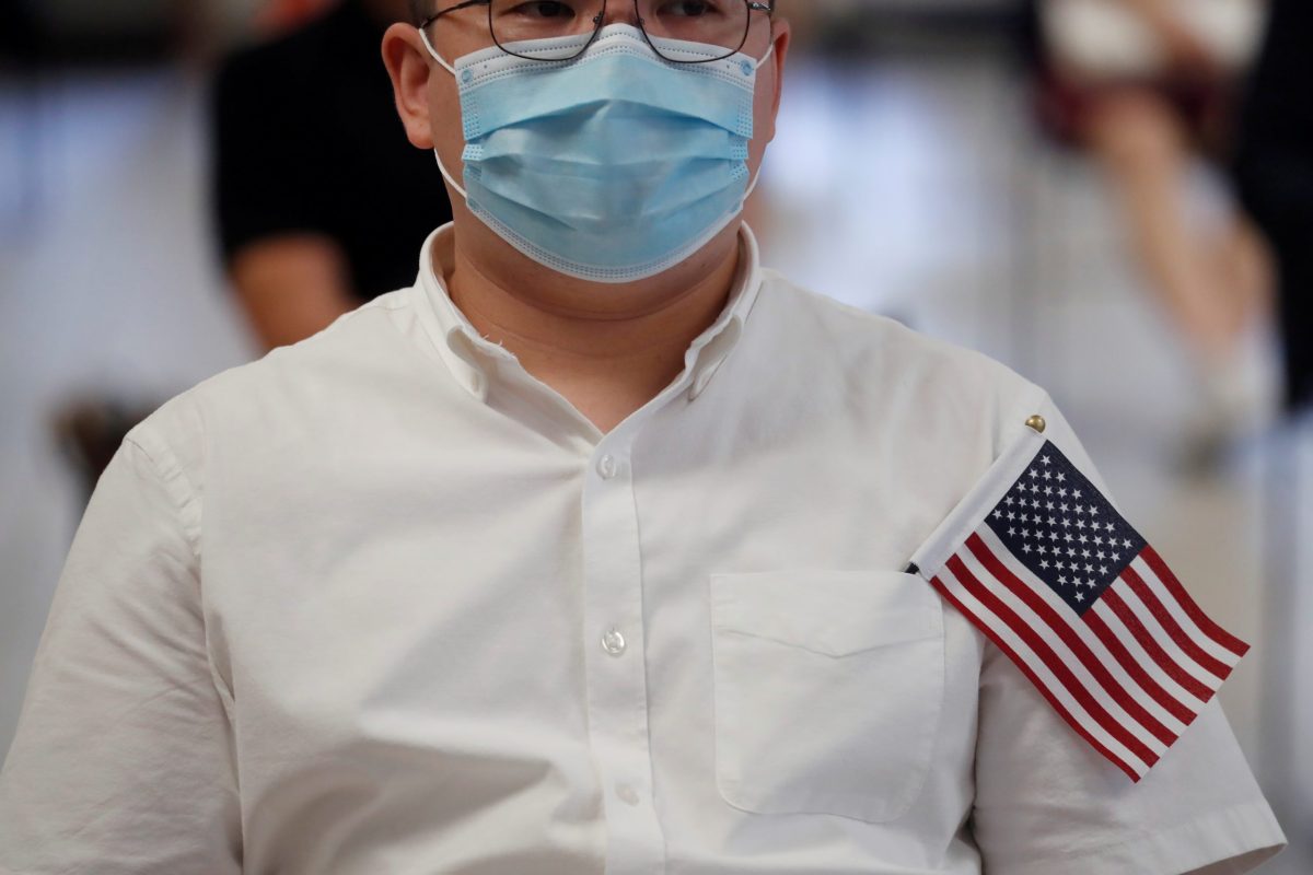 FILE PHOTO: A citizen candidate sits socially distanced and wearing a protective face mask, as the outbreak of the coronavirus disease (COVID-19) continues, during a U.S. Citizenship and Immigration Services (USCIS) naturalization ceremony in New York City