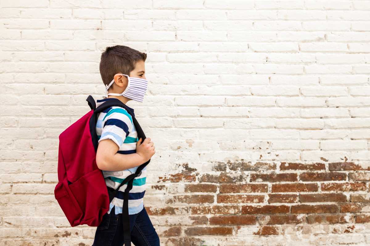 Little boy going to school with protective mask