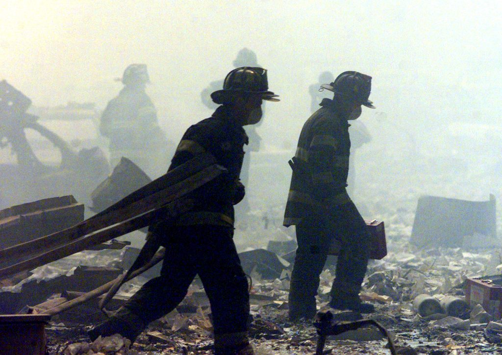 FIREFIGHTERS WALK AMID RUBBLE AT WORLD TRADE CENTER.