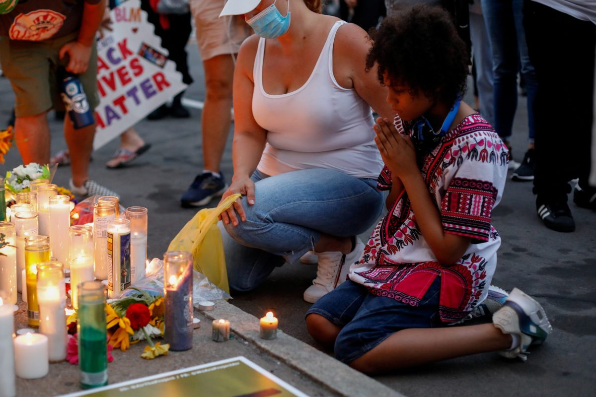 Demonstrators kneel in front of a memorial during a protest in Rochester, New York