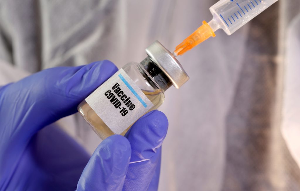 FILE PHOTO: A woman holds a small bottle labeled with a “Vaccine COVID-19” sticker and a medical syringe in this illustration