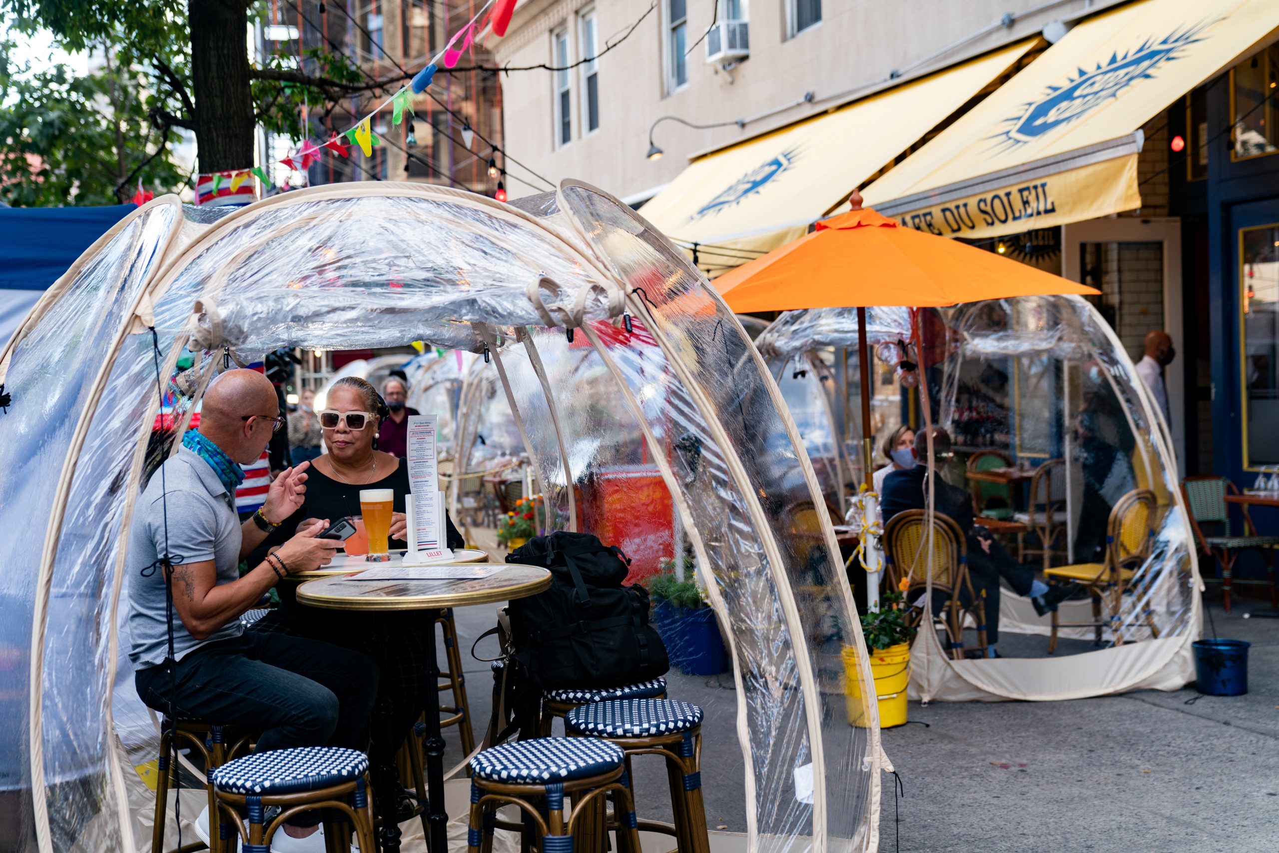 People sit outside Cafe Du Soliel under bubble tents