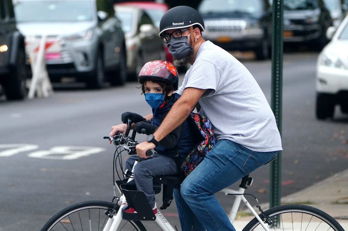 A child and parent ride a bike past P.S. 130