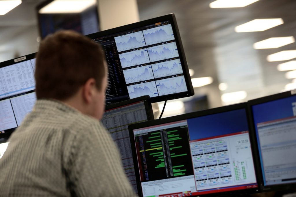 FILE PHOTO: Traders looks at financial information on computer screens on the IG Index trading floor