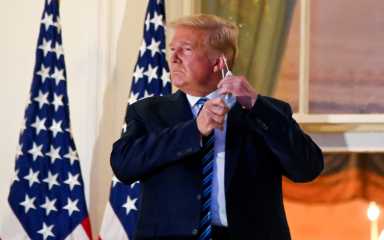 FILE PHOTO: U.S. President Donald Trump pulls off his face mask as he returns to the White House after being hospitalized at Walter Reed Medical Center for coronavirus disease (COVID-19)