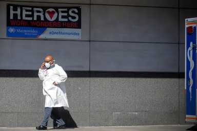 A doctor speaks on his phone outside the Emergency entrance to Maimonides Medical Center in the Borough Park neighborhood of Brooklyn, New York