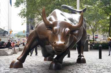 FILE PHOTO: People pose for a photo at the Charging Bull statue, also known as the Wall St. Bull, is pictured in the financial district