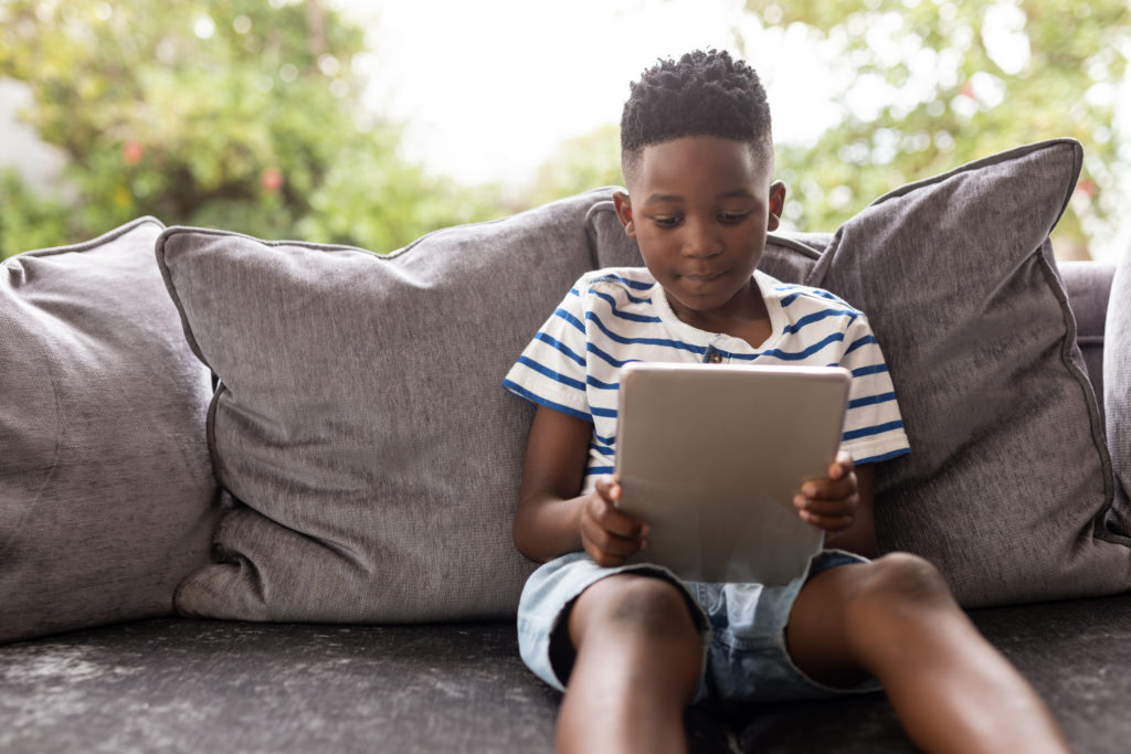Boy using digital tablet on a sofa in living room