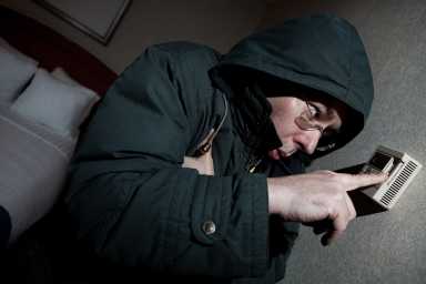 Freezing man adjusting thermostat