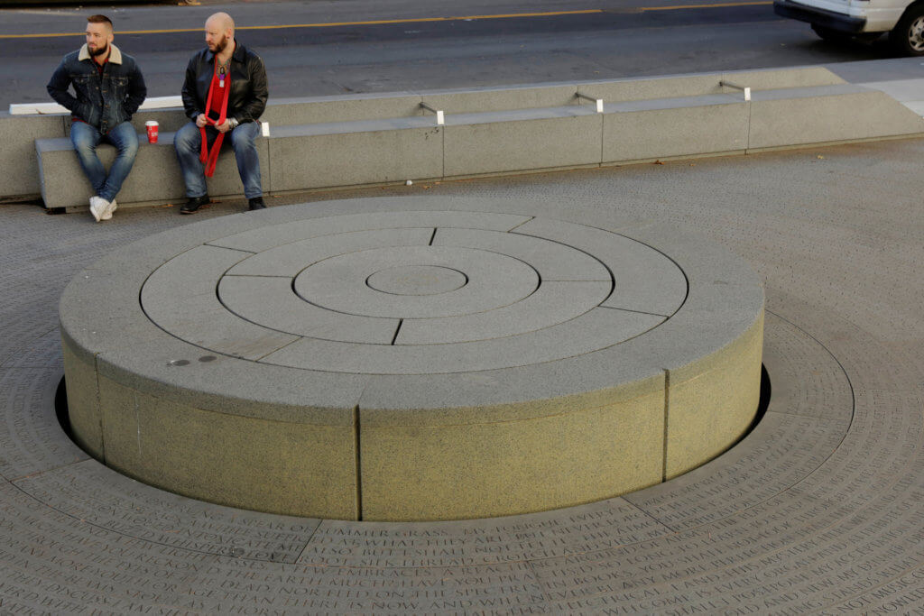 Two men sit and talk while visiting the New York City AIDS Memorial on World AIDS Day in New York