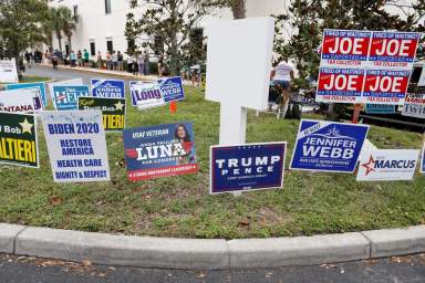 FILE PHOTO: Campaign signs are posted near the Supervisor of Elections Office polling station while people line up for early voting in Pinellas County ahead of the election in Largo