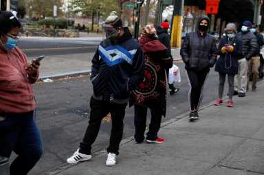People wearing protective face masks wait in line outside a CityMD Urgent Care, as the global outbreak of the coronavirus disease (COVID-19) continues, in the Bronx borough of New York