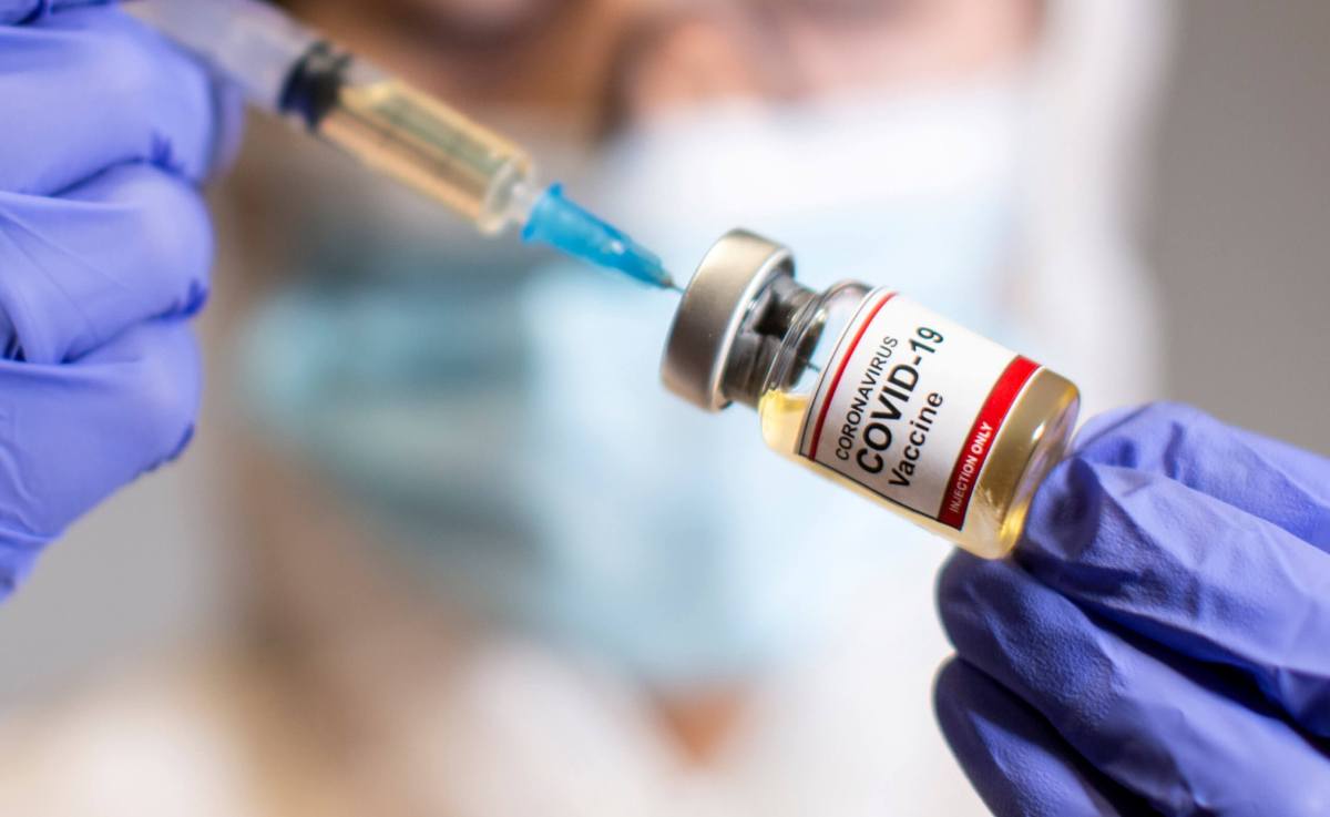 FILE PHOTO: A woman holds a small bottle labeled with a “Coronavirus COVID-19 Vaccine” sticker and a medical syringe in this illustration