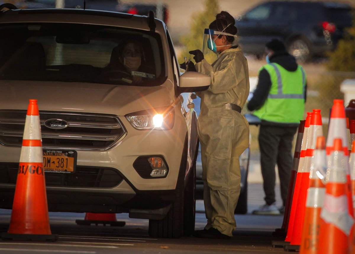 A health worker provides a COVID-19 test at a drive-through testing site, in Staten Island, New York