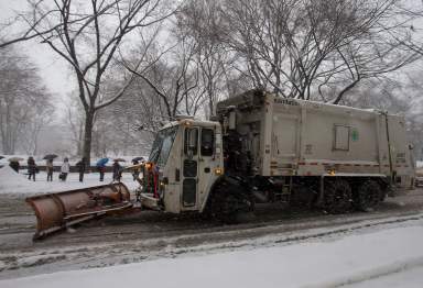 Garbage truck plows along 5th Avenue at Central Park as it snows in New York