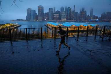 FILE PHOTO: A man runs along the Brooklyn Heights Promenade as fog covers lower Manhattan in New York
