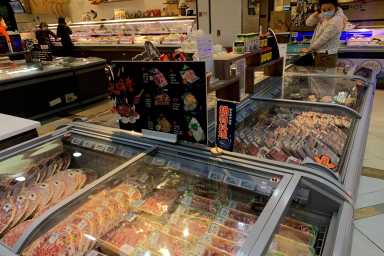 FILE PHOTO: Woman checks imported frozen meat at a supermarket in Beijing