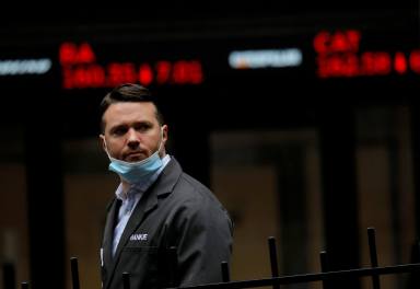 FILE PHOTO: FILE PHOTO: A trader walks past a digital stock price display outside the New York Stock Exchange in New York