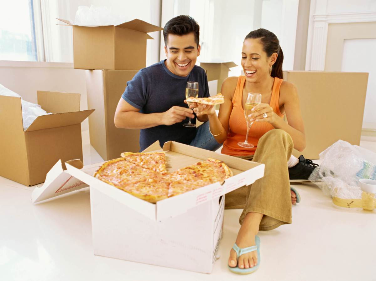 close-up of a young couple holding a slice of pizza and champagne flutes