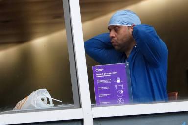 A hospital worker puts his personal protective equipment back on after lunch in New York