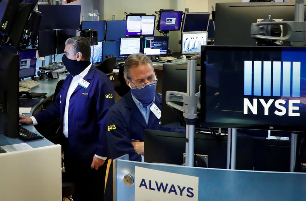 FILE PHOTO: Traders wearing masks work, on the first day of in person trading since the closure during the outbreak of the coronavirus disease (COVID-19) on the floor at the NYSE in New York