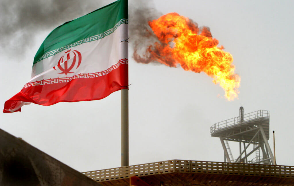 FILE PHOTO: A gas flare on an oil production platform is seen alongside an Iranian flag in the Gulf