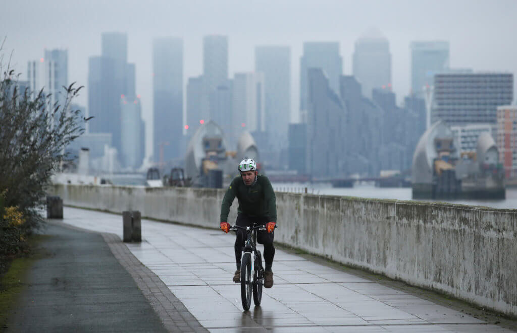 FILE PHOTO: Buildings are seen in the Canary Wharf business district, as a man cycles along a path, amid the outbreak of the coronavirus disease (COVID-19), in London