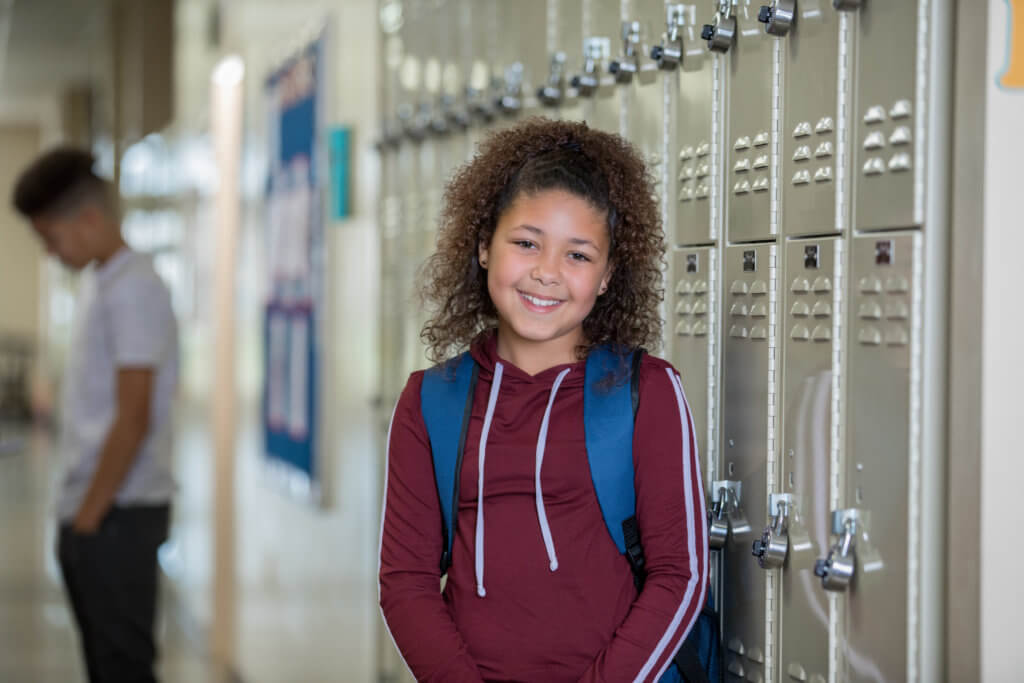 Teen girl standing by lockers in corridor