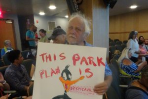 Hearing attendee poses with his sign - Photo by William Engel