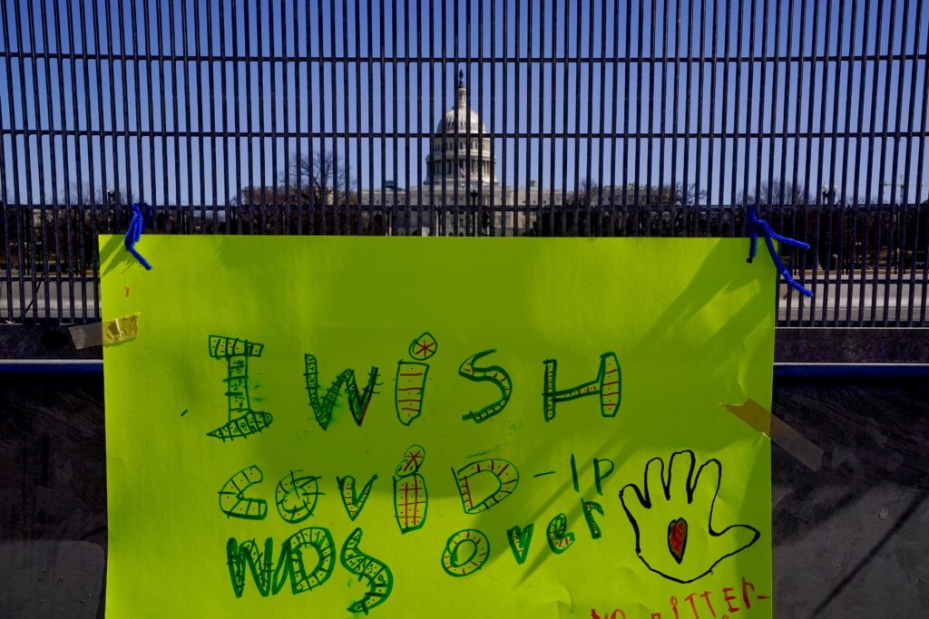 A sign reading, “I wish Covid-19 was over” is seen on security fence surrounding the U.S. Capitol in Washington