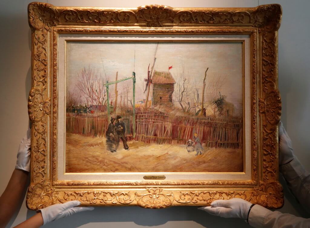 Sotheby’s Paris employees pose with the painting “Scene de rue a Montmartre” by Dutch painter Vincent Van Gogh