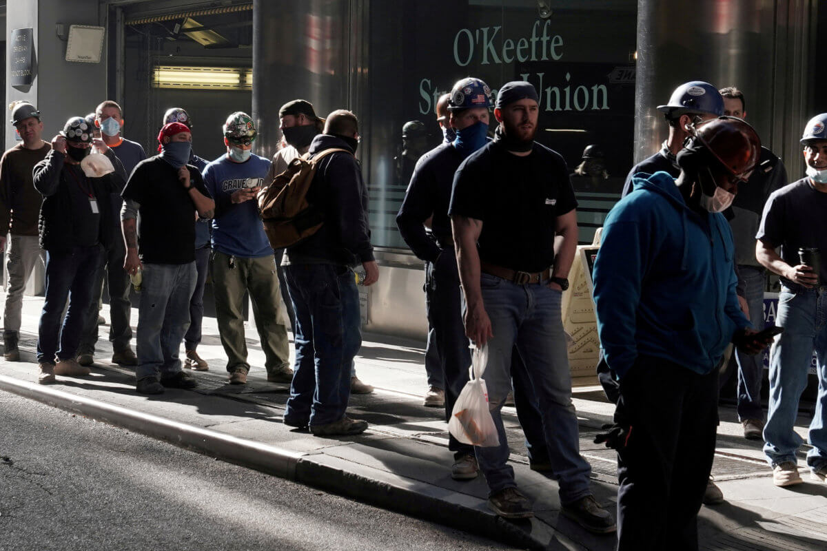 FILE PHOTO: Construction workers wait in line to do a temperature test to return to the job site