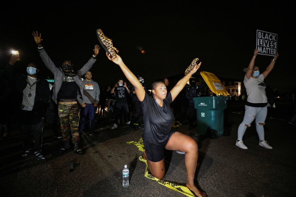 A woman who was tear gassed while confronting police raises her arms after police allegedly shot and killed a man, in Brooklyn Center, Minnesota