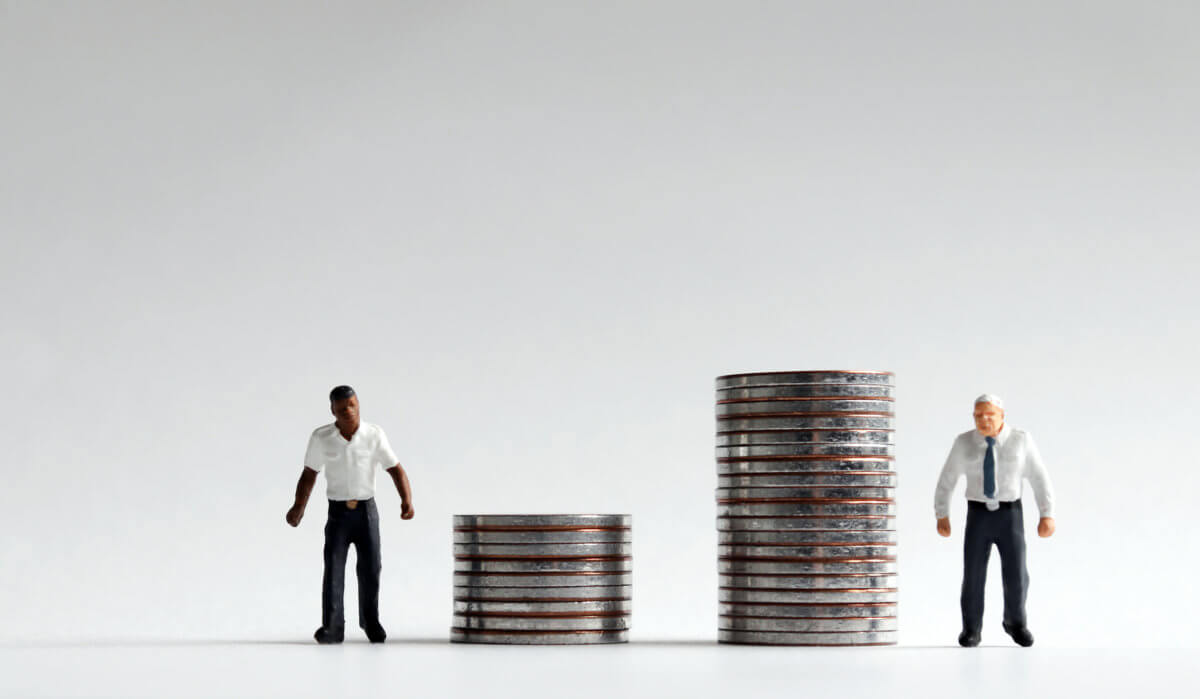 An unfair concept of wage discrimination. Miniature people standing on a pile of coins.