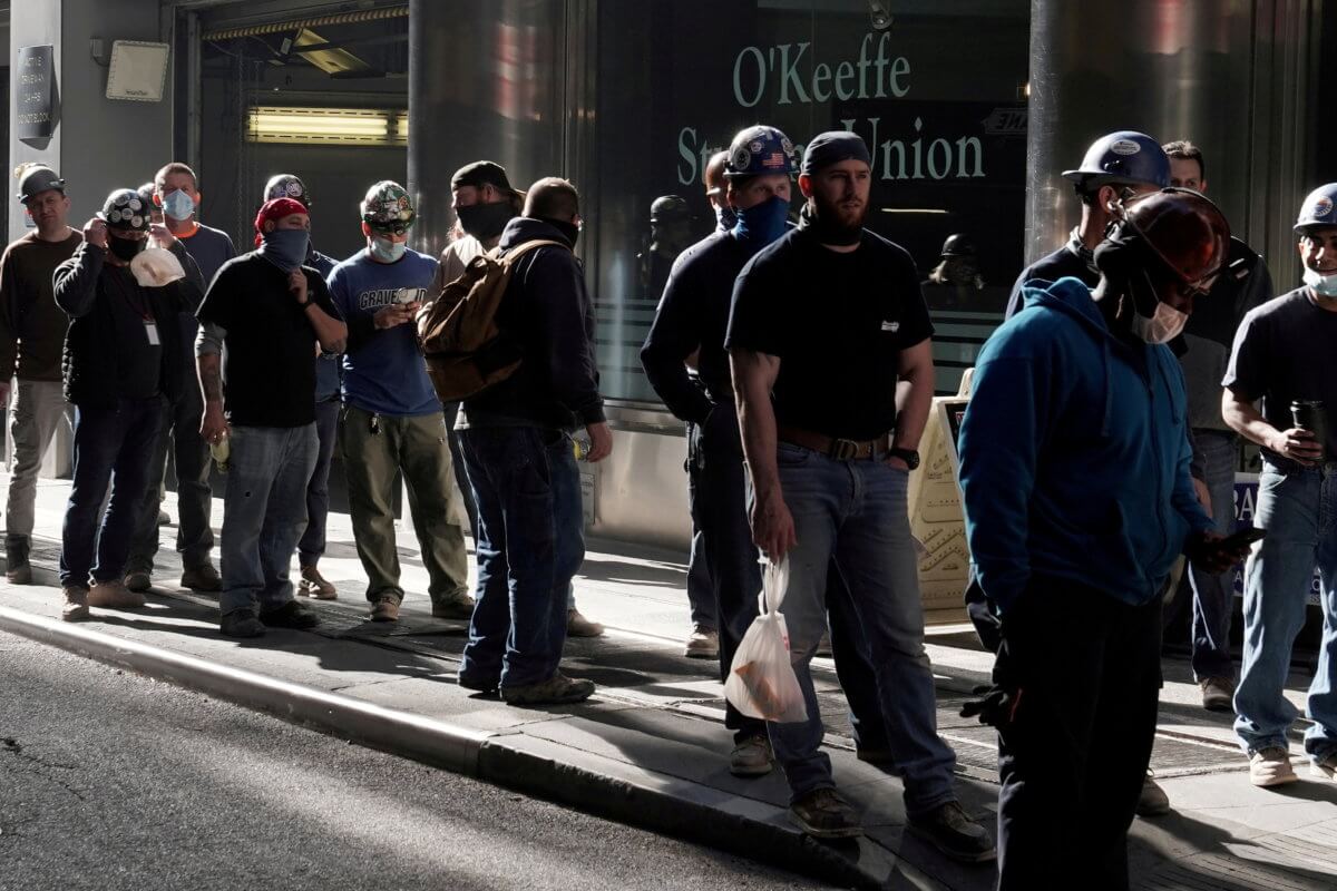 FILE PHOTO: Construction workers wait in line to do a temperature test to return to the job site