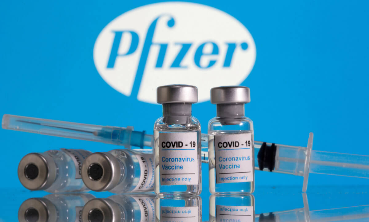 FILE PHOTO: Vials labelled “COVID-19 Coronavirus Vaccine” and a syringe are seen in front of the Pfizer logo in this illustration