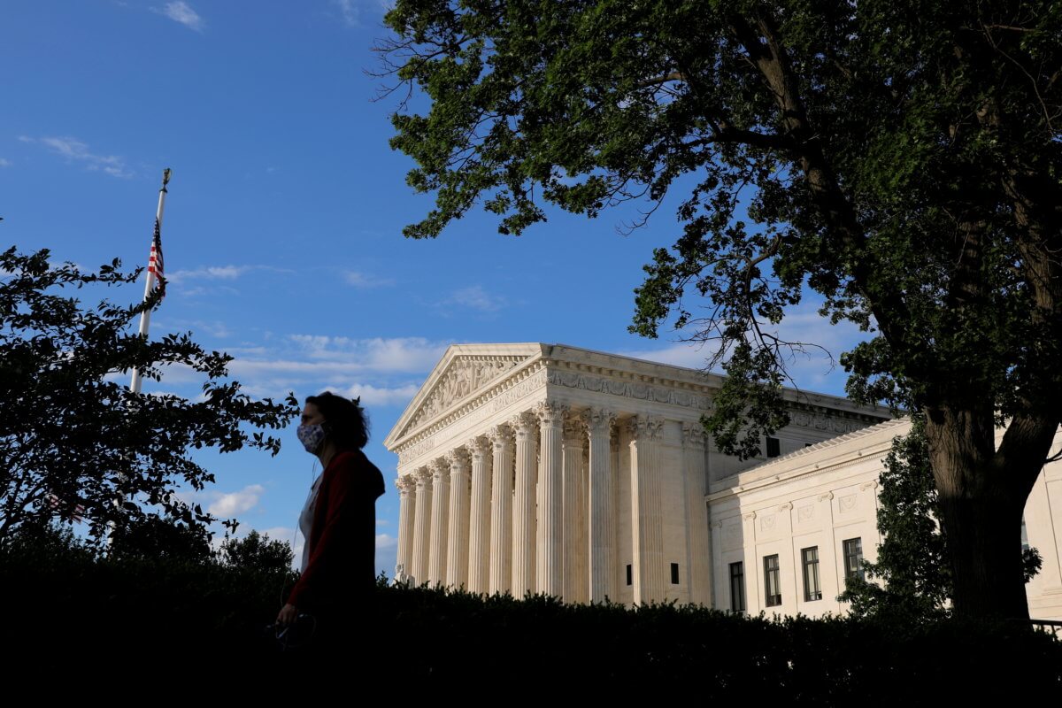 FILE PHOTO: A person in a mask walks past the United States Supreme Court Building in Washington, D.C.
