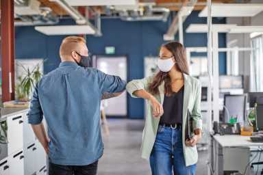 Business colleagues greeting with elbow in office