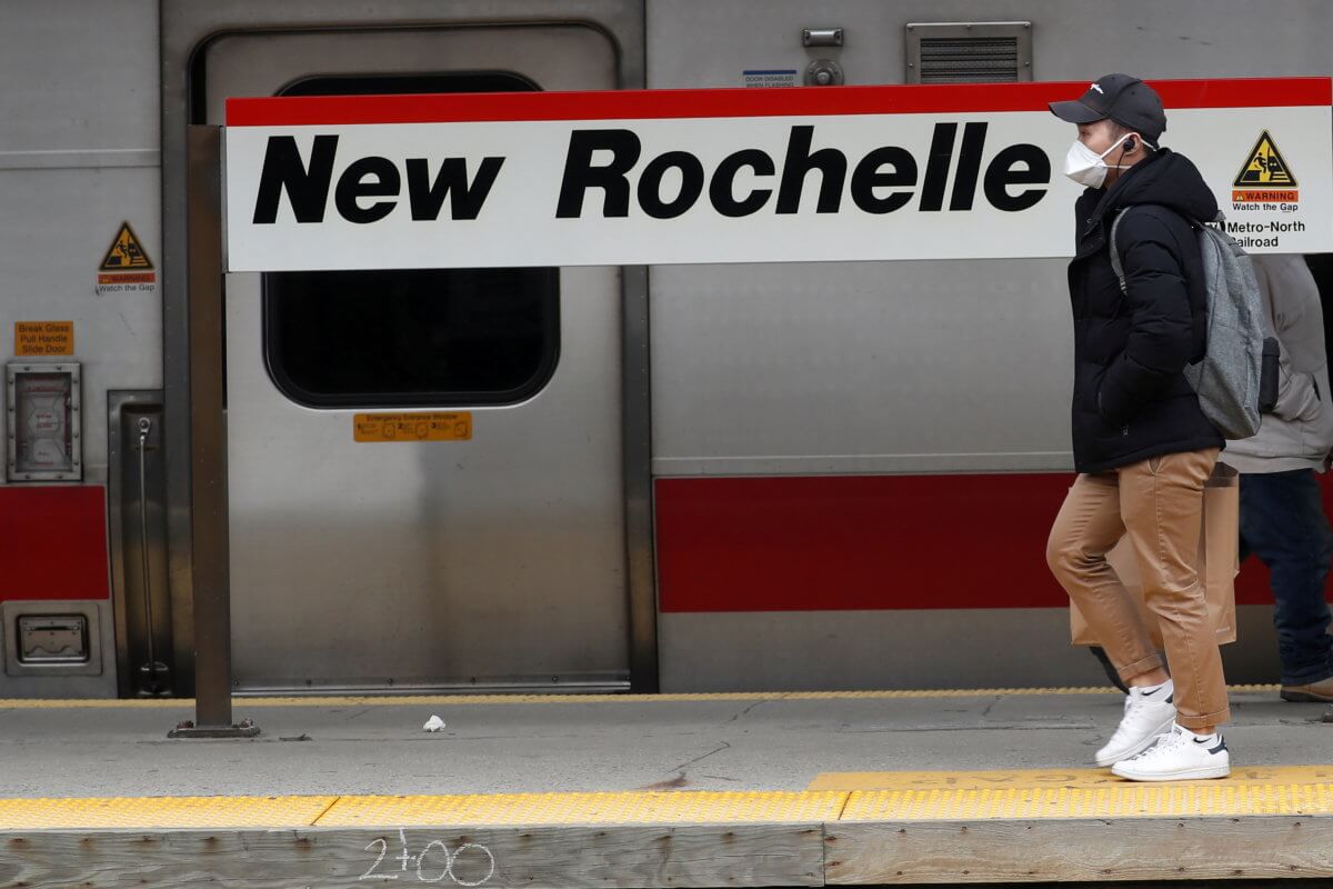 FILE PHOTO: A man wears a mask as he walks on a commuter train platform in New Rochelle New York