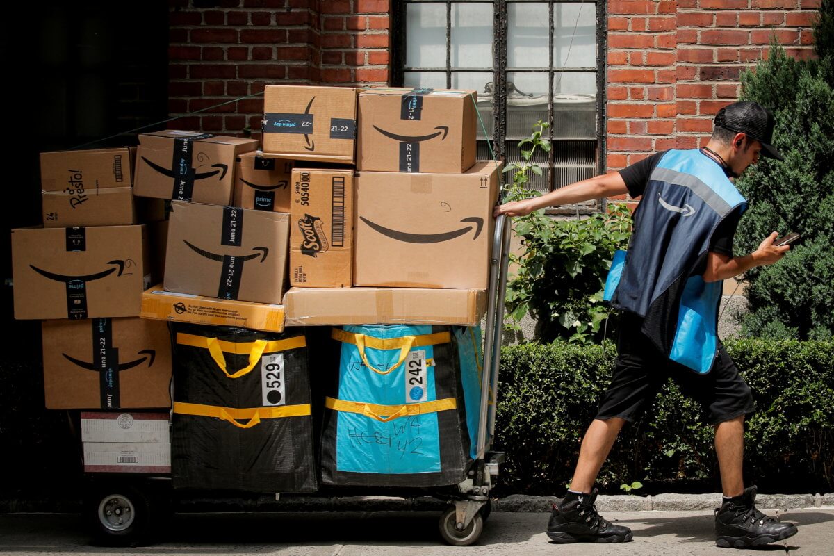 FILE PHOTO: An Amazon delivery worker pulls a delivery cart full of packages during its annual Prime Day promotion in New York