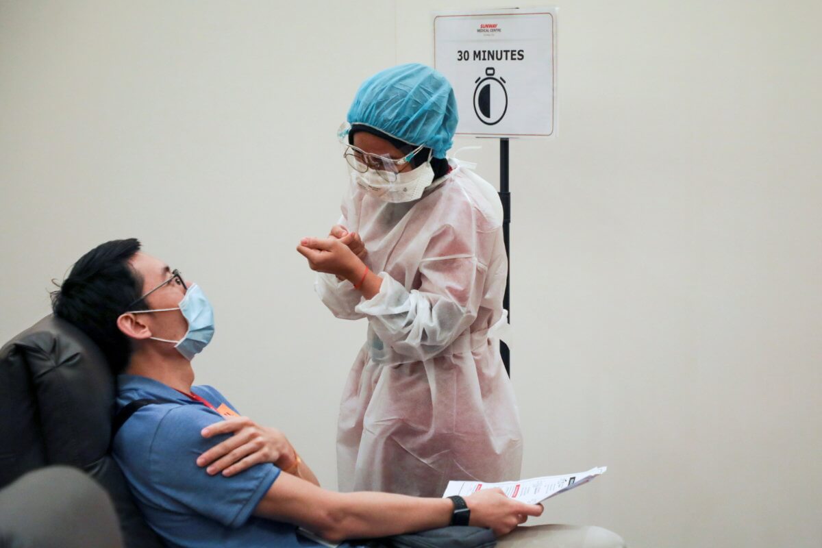FILE PHOTO: A medical worker speaks to a man under observation after receiving coronavirus disease (COVID-19) vaccine, at Sunway Medical Centre, in Subang Jaya